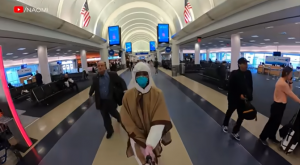 Naomi Campbell in full PPE walking through an airport.