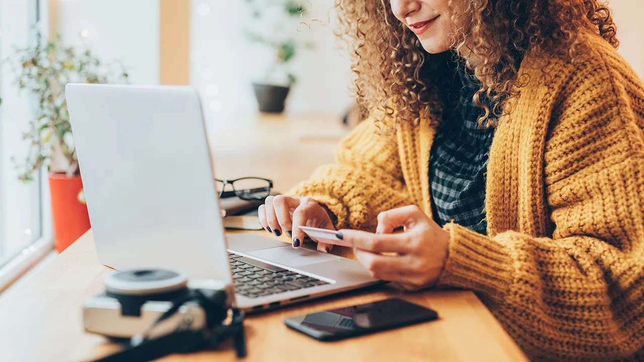 Young woman shopping online in cafe with laptop. (Photo by filadendron/Getty Images)