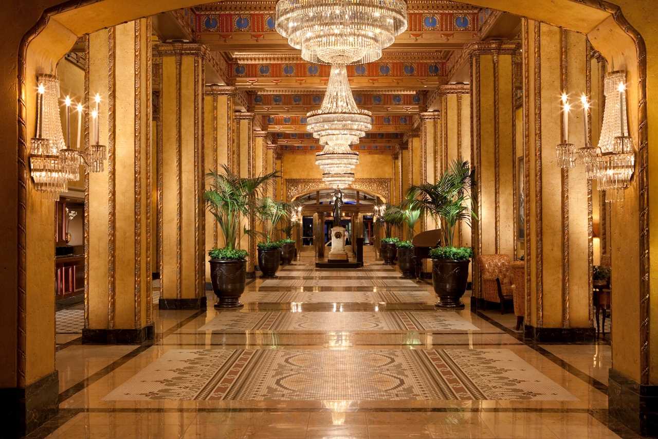 gold-themed hotel lobby with large chandeliers and plants