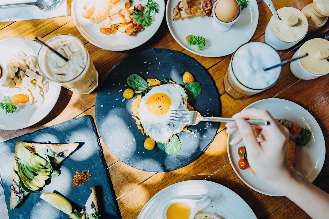 Directly above view of woman sharing a variation of meal in an outdoor restaurant against beautiful sunlight