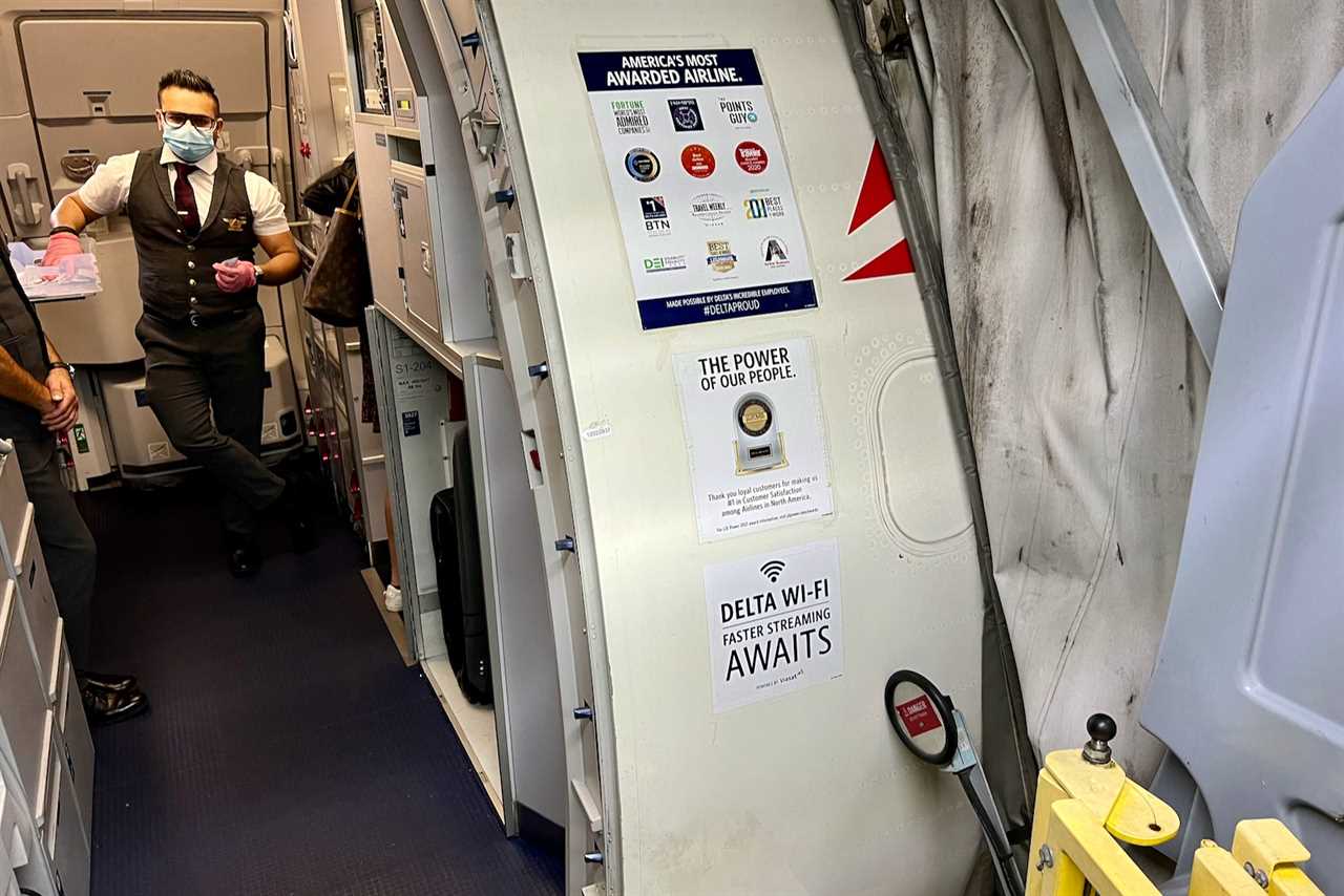 an open door leads into a Delta plane with a flight attendant waiting beyond; a large decal next to the open door indicates the new Delta wi-fi is on this plane