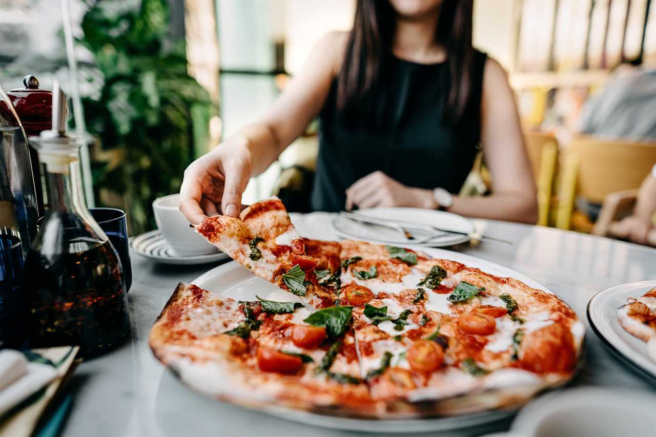 Close up of young Asian woman enjoying freshly made pizza in an Italian restaurant