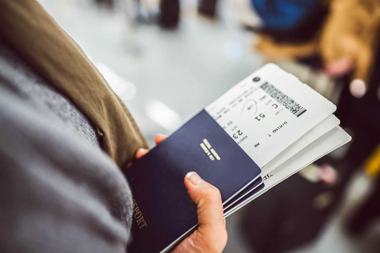 Woman’s hands holding passports & boarding passes of her family while waiting at the check-in counter in the airport