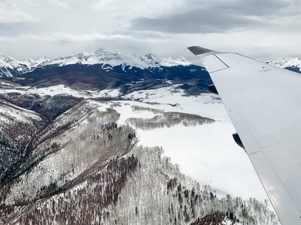 a snow-covered mountain and wing of airplane as seen from the window