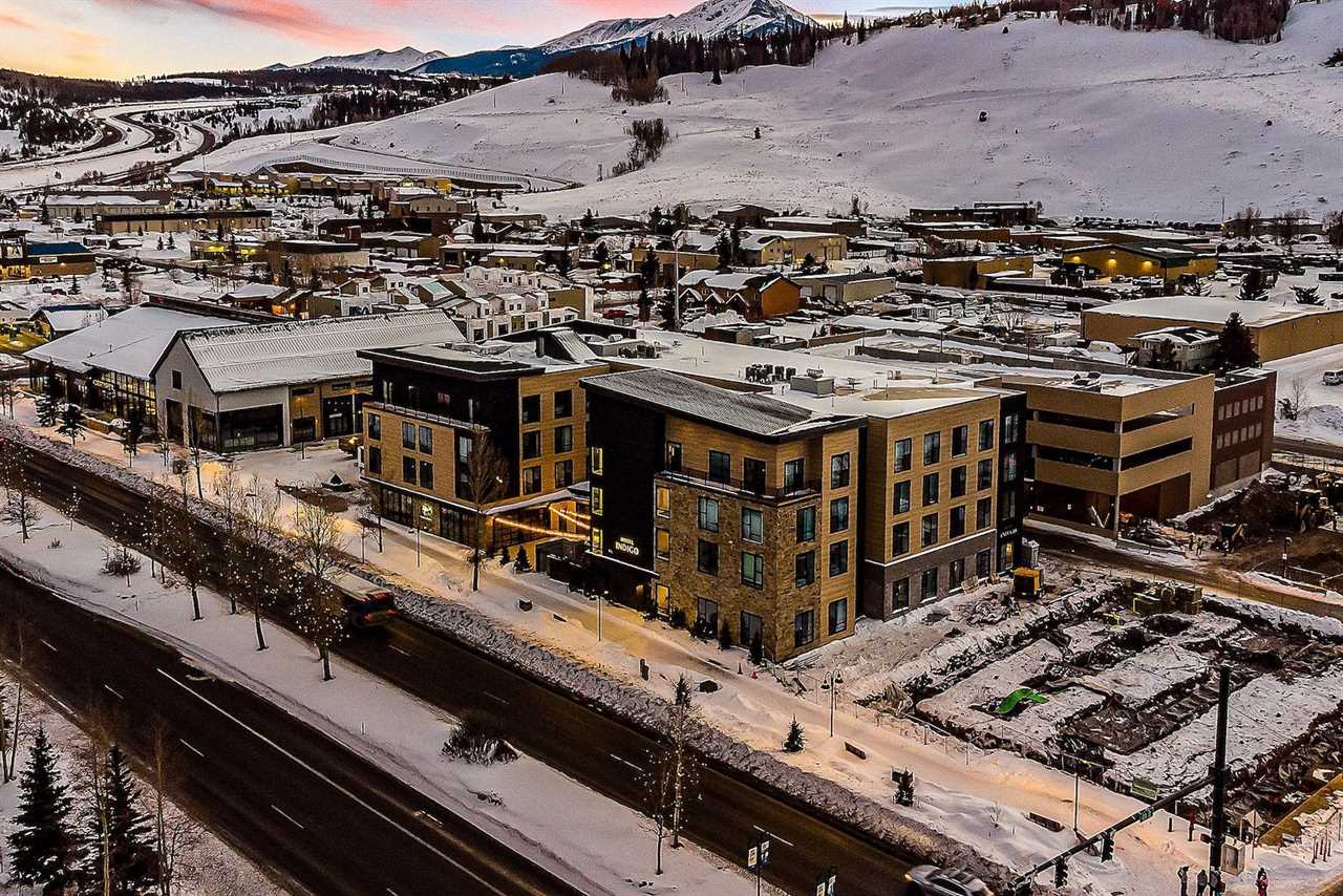 A hotel surrounded by parking lots with snow-covered mountains in the background