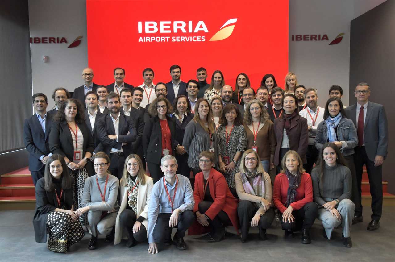 Iberia airport services staff pose in front of a logo.