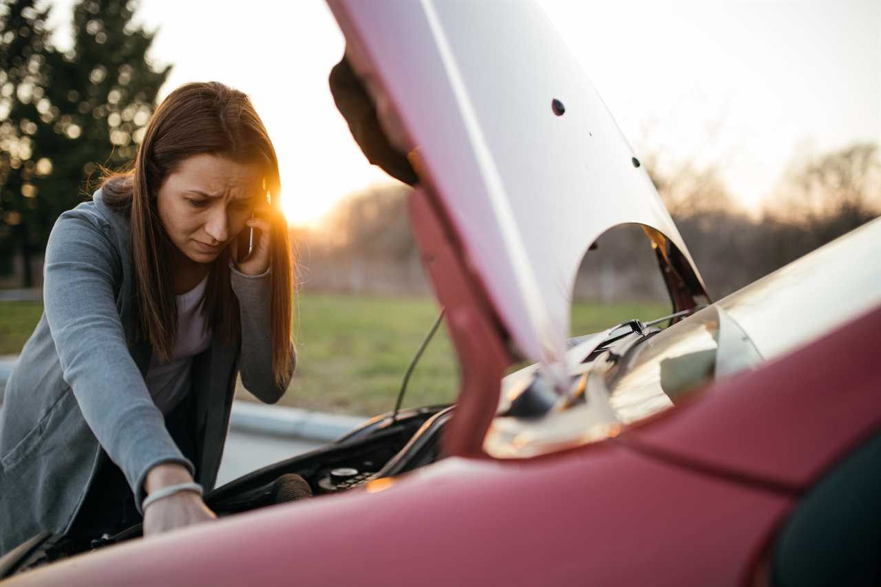 a woman makes a phone call while looking at the engine of her car