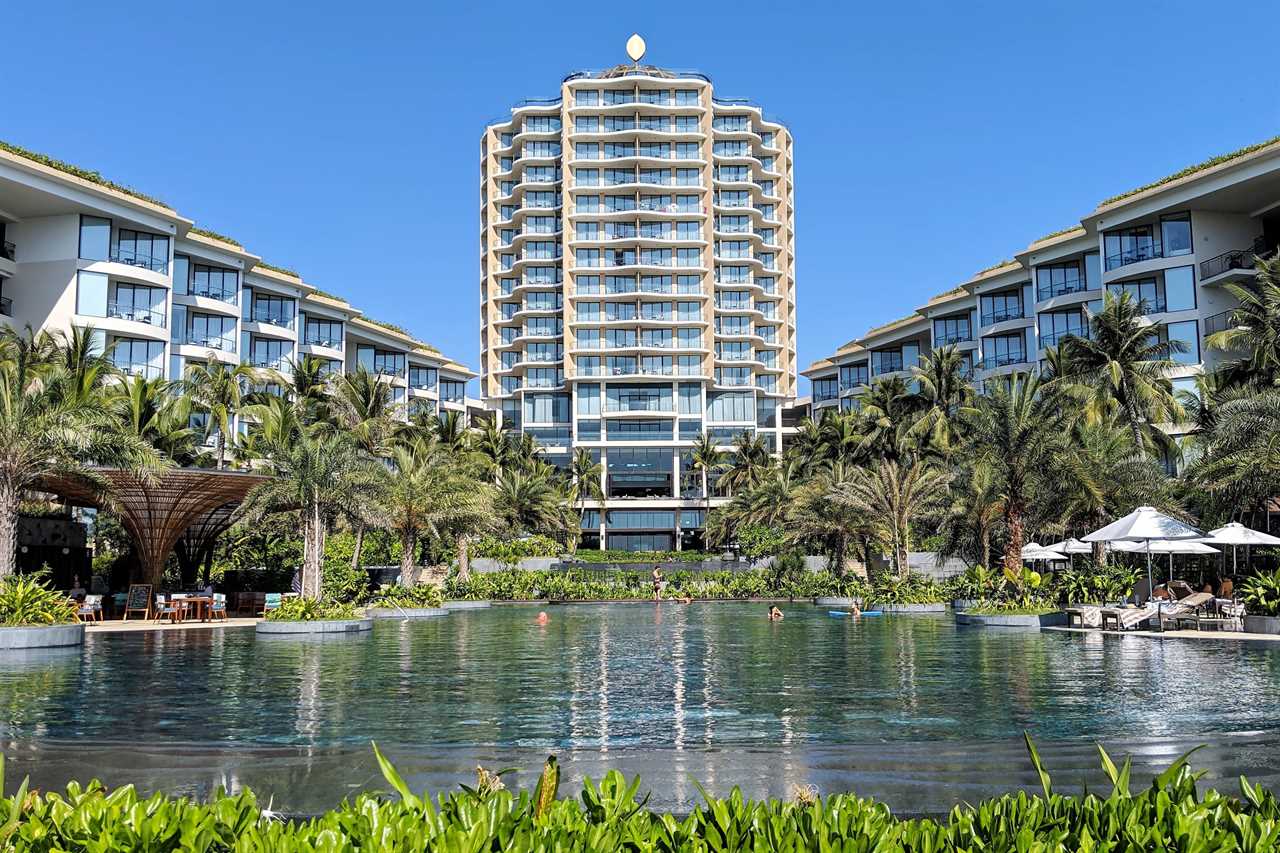 a hotel pool in the foreground with a large hotel tower in the background