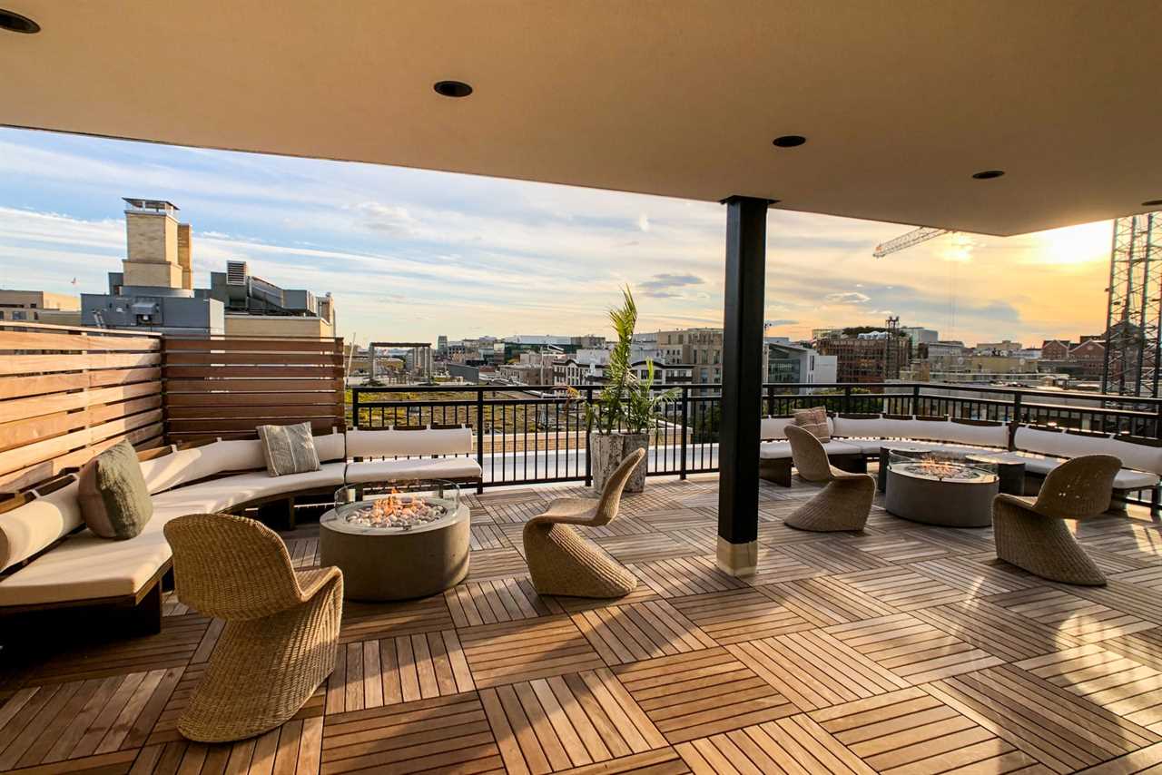 sunset is visible beyond a city, as seen from an outdoor terrace at a hotel