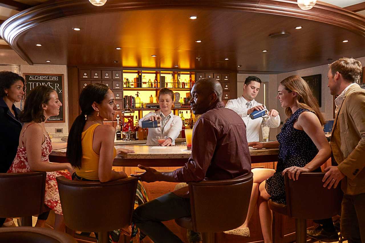 Couples sitting at bar while bartenders pour cocktails