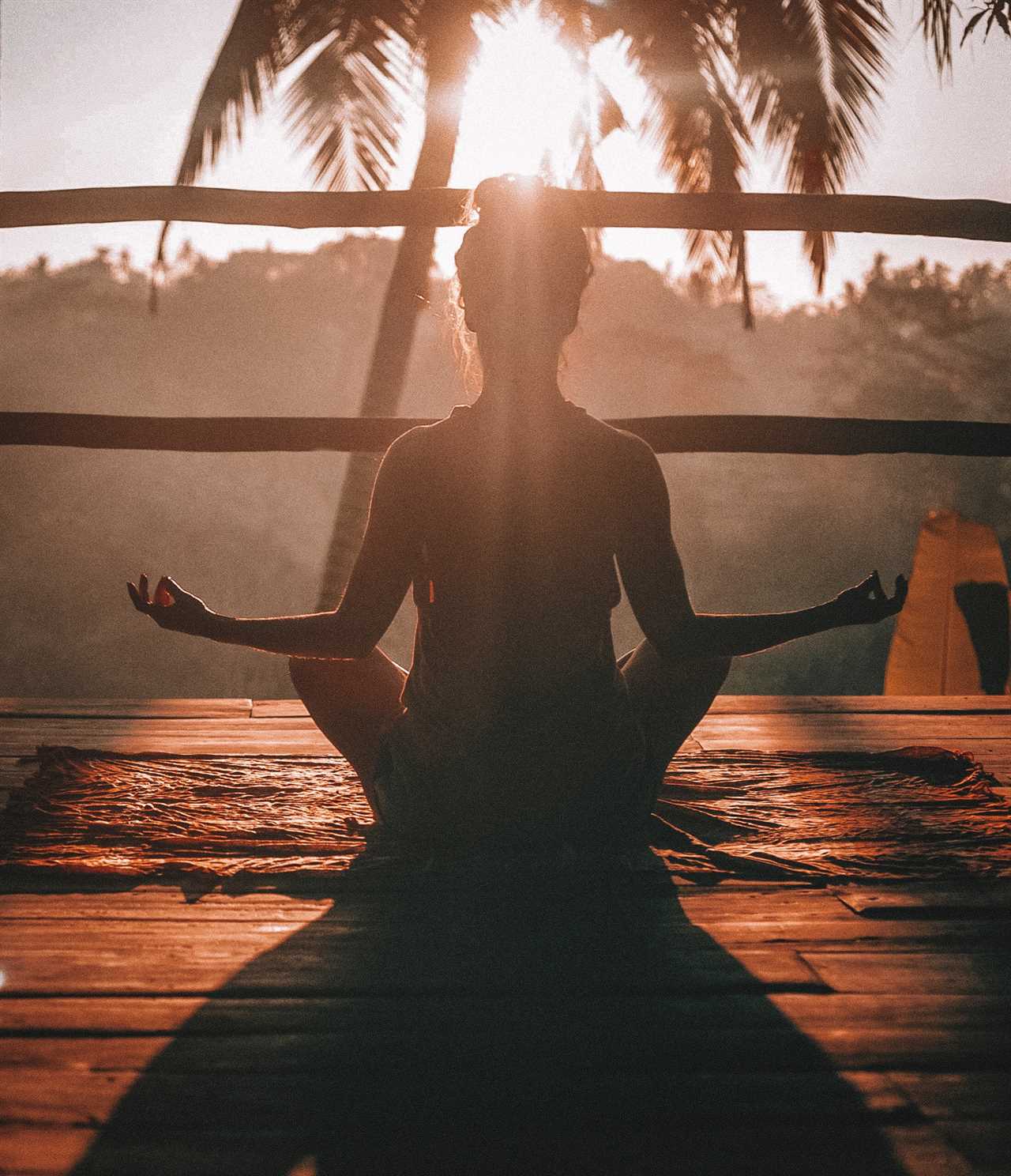 The silhouette of a woman meditating in the sunlight