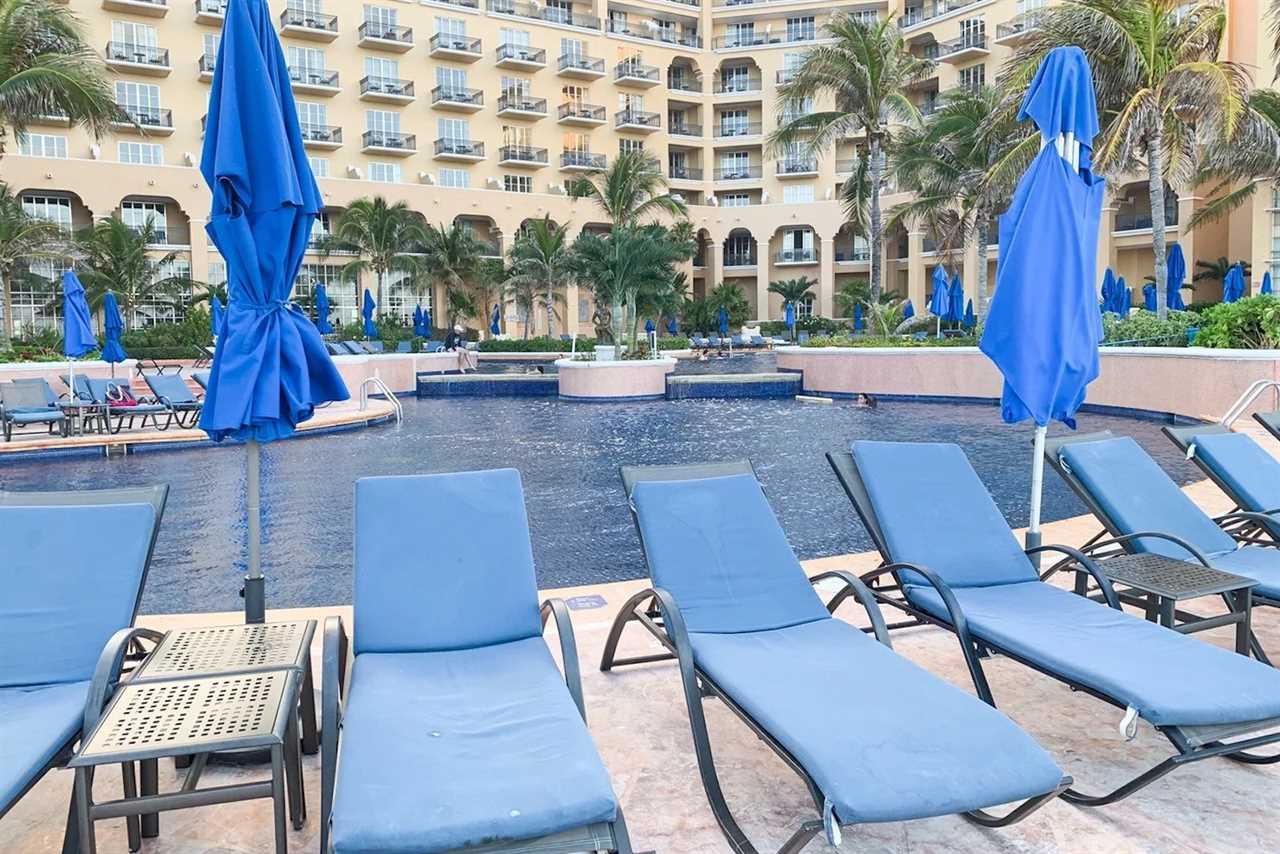 lounge chairs in front of hotel pool, hotel building behind