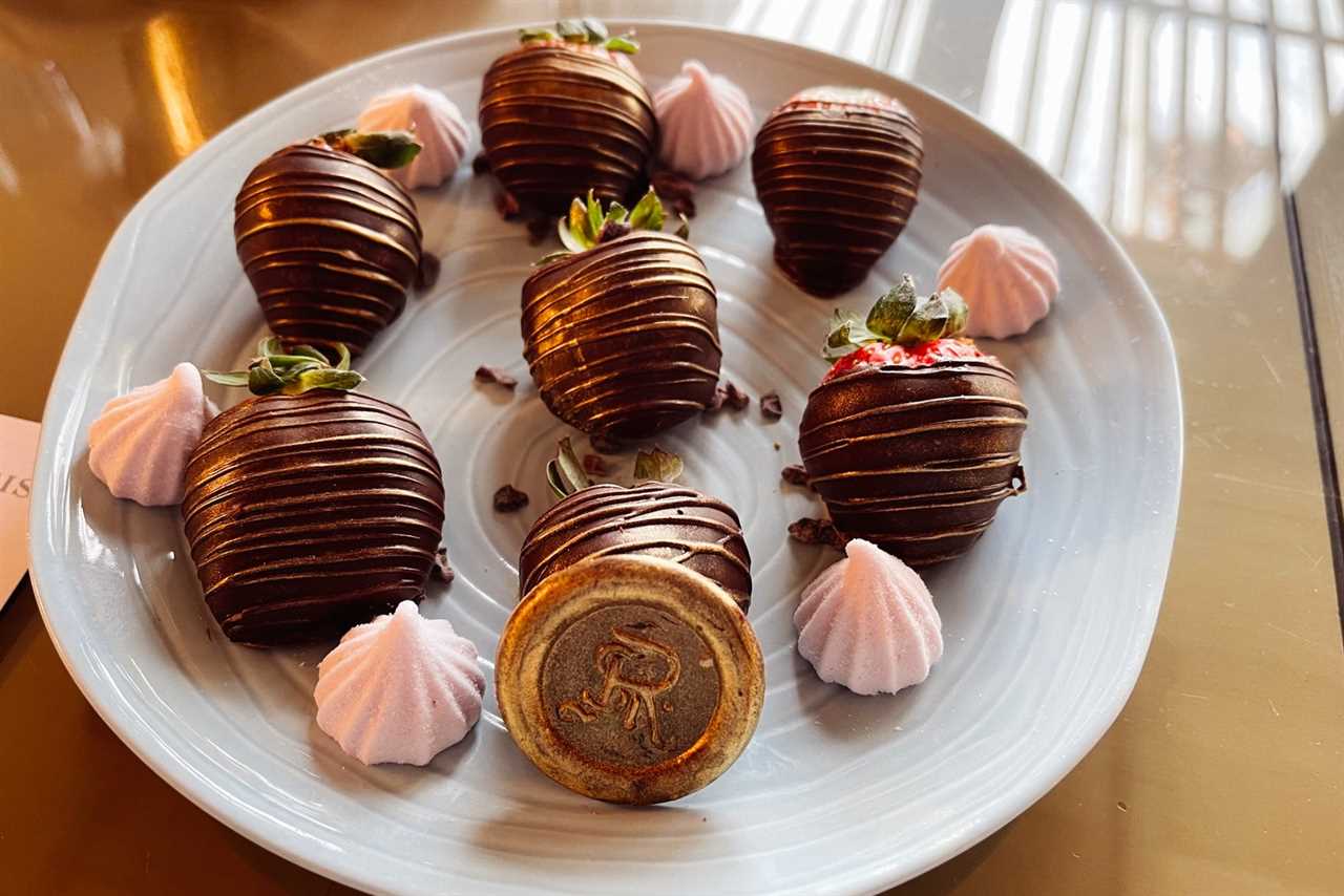 a platter of chocolate-covered strawberries with a gold 