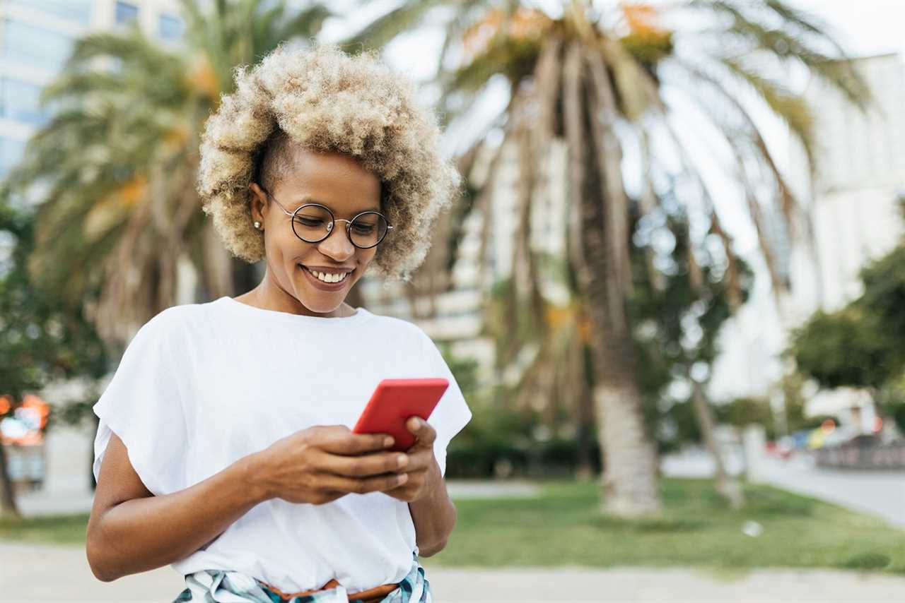 Woman smiling while using a mobile phone outdoors