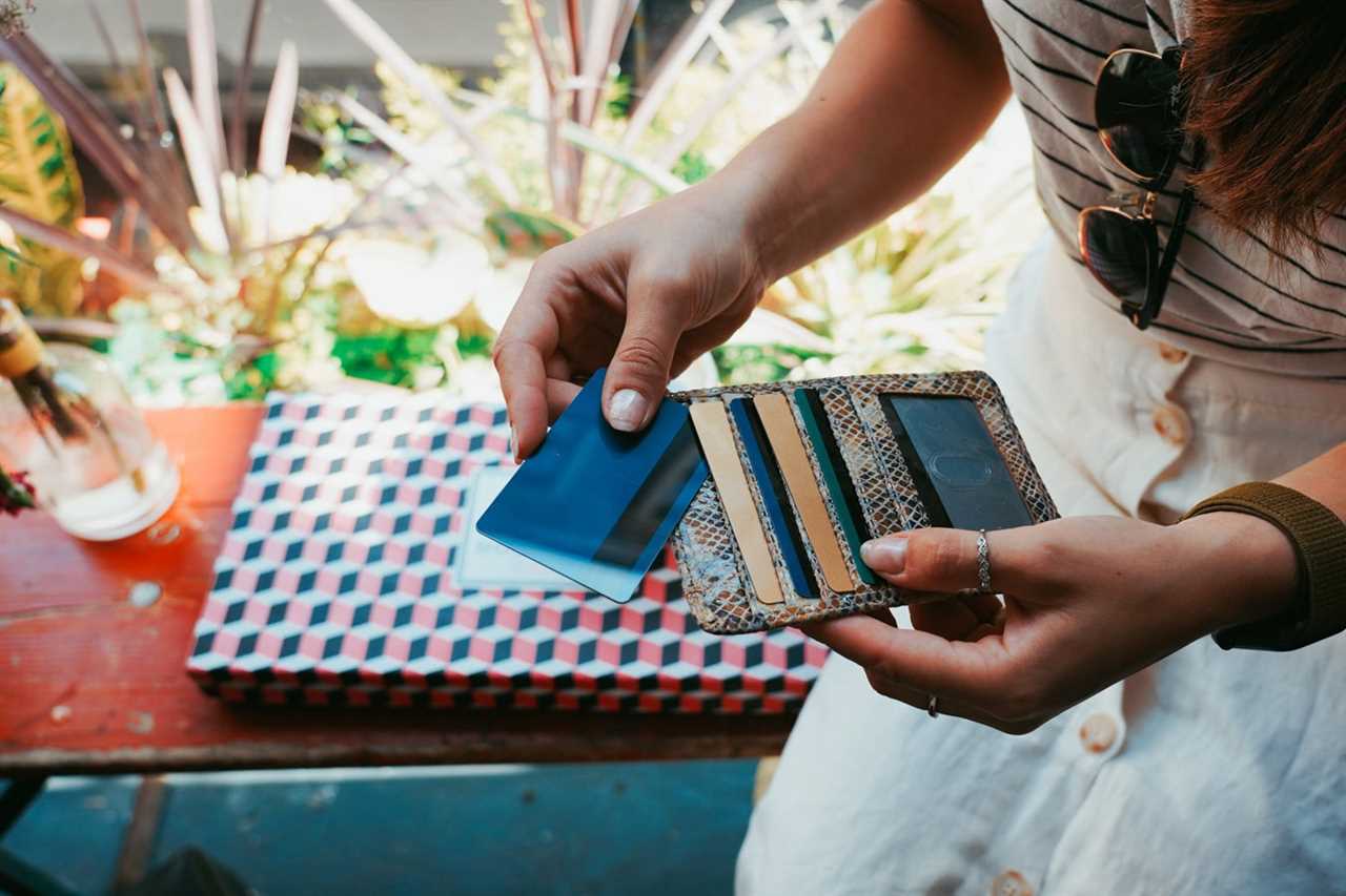 an unknown person holds a wallet with many credit cards while sitting outdoors