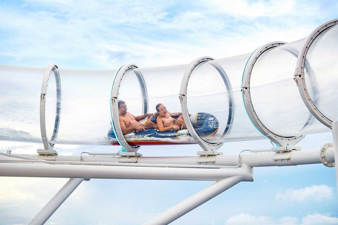 Two cruise passengers on double raft going through clear tube slide