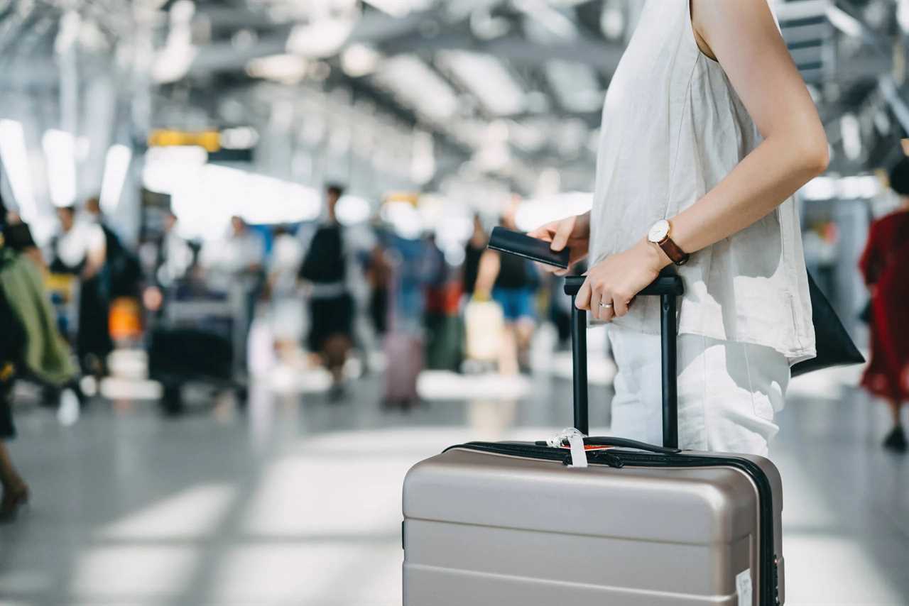 Cropped image of young woman holding passport and suitcase walking in the international airport hall. d3sign/Getty