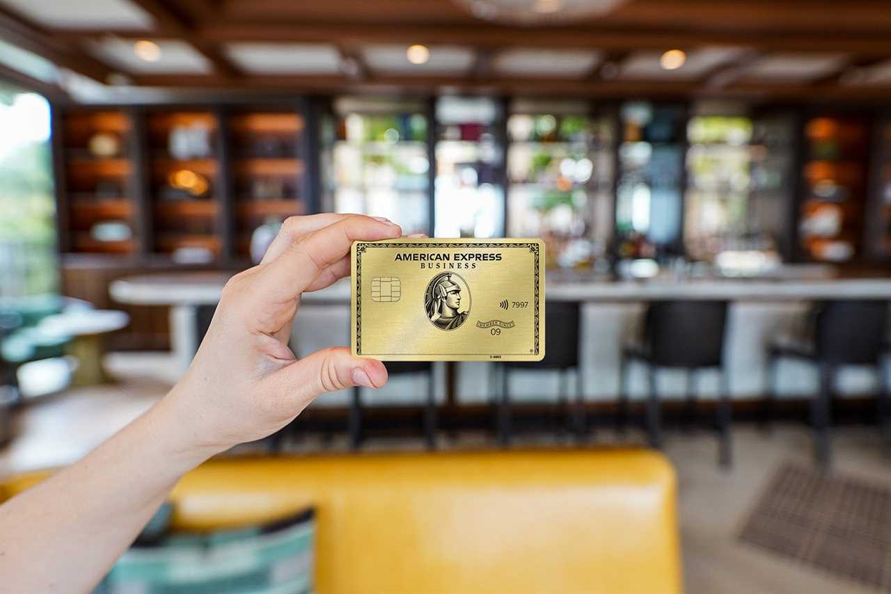 a hand holds a credit card with a bar in the background