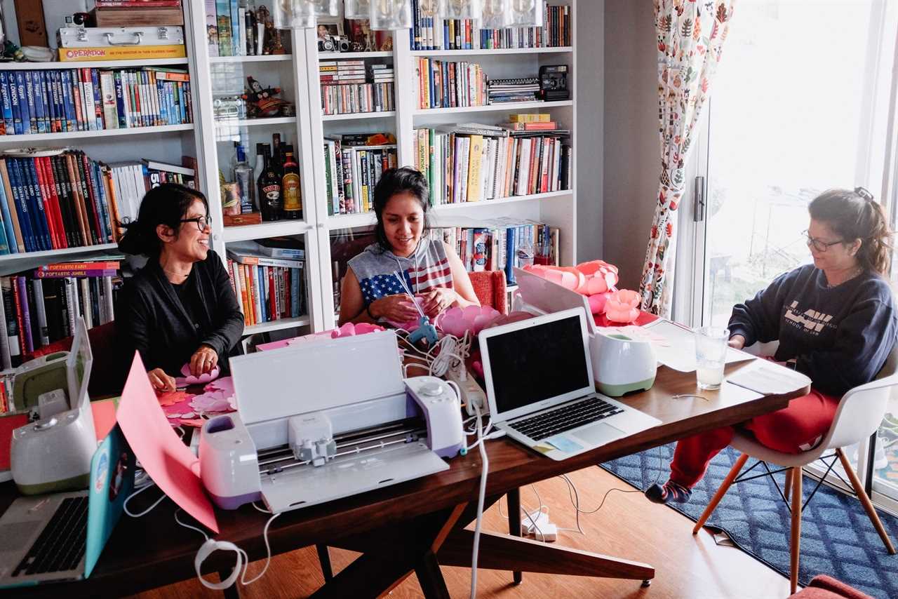 photo shows several people working on computers and talking at a table inside a home