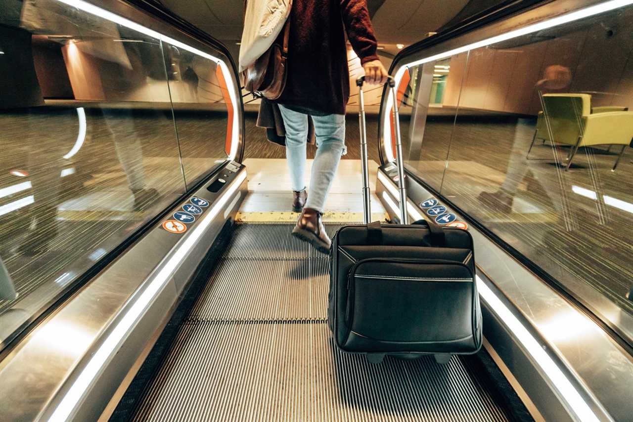 Person with rolling luggage on people mover