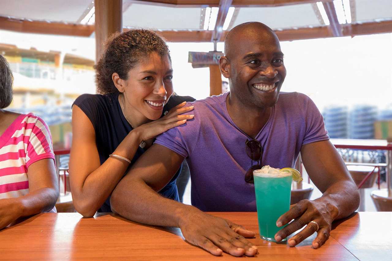 Black couple with a blue-green drink at an outdoor cruise ship bar