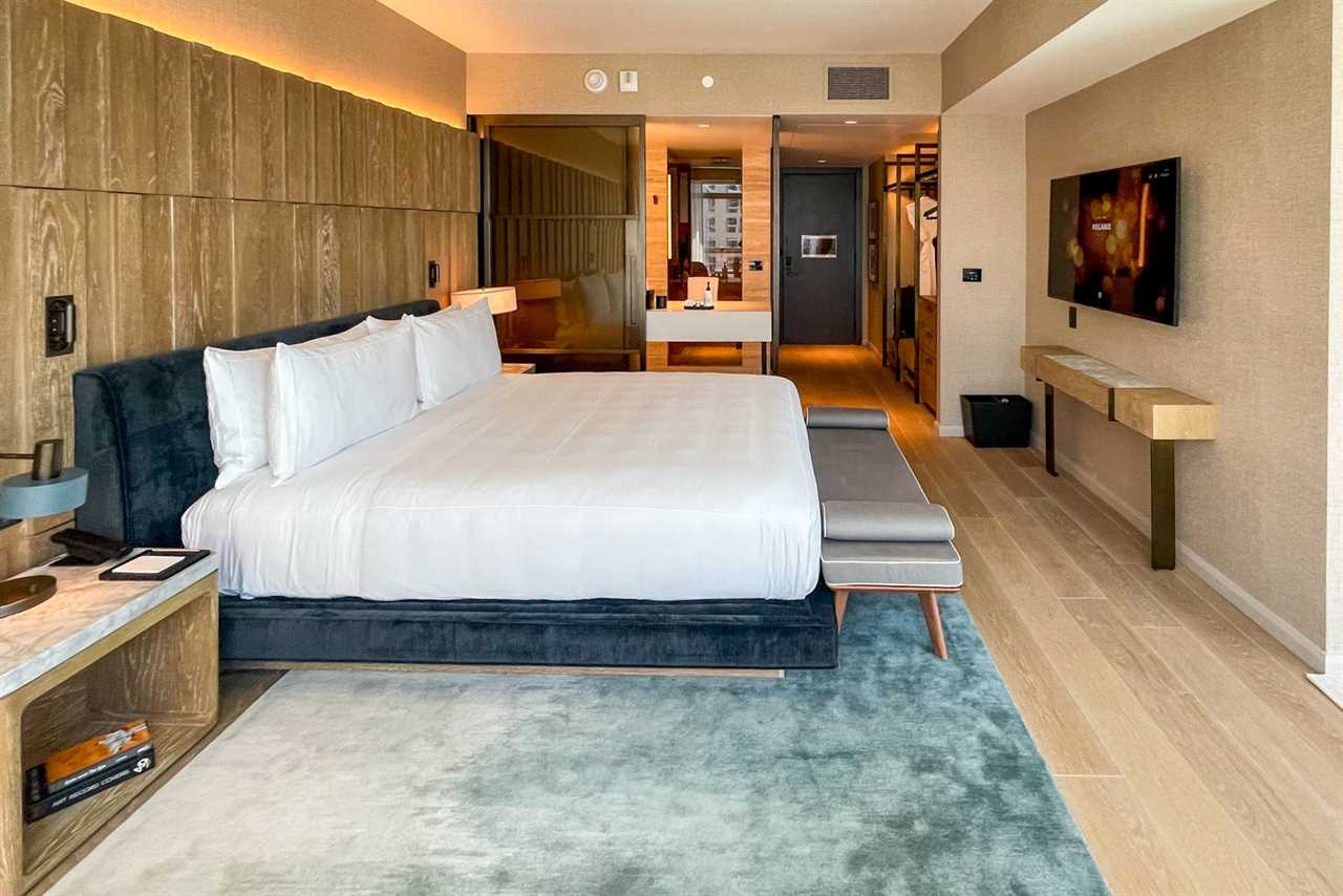 a king-sized bed inside a luxury hotel room, showing the bathroom beyond
