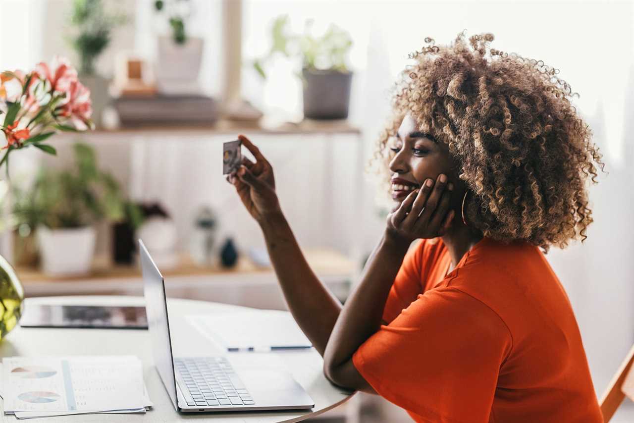 Woman looking at credit card while using a laptop