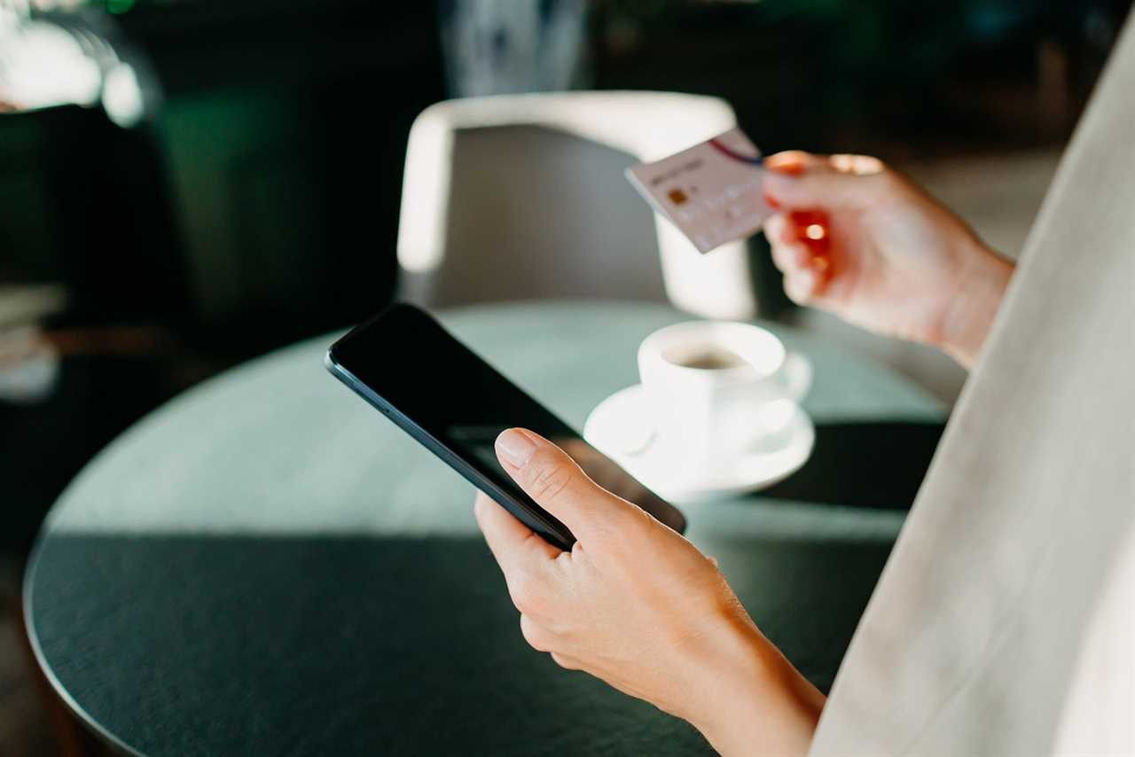 Closeup of a person holding a phone in their left hand and a credit card in their right